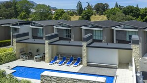A modern hotel with a rooftop pool area, outdoor seating, and a view of the surrounding landscape. - Water Views Apartment | Stylish 3BR Villa with Pool & Lake Access (Taupō)