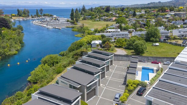 A coastal residential area with modern buildings, a marina, and a clear view of the sea. - Water Views Apartment | Stylish 3BR Villa with Pool & Lake Access (Taupō)