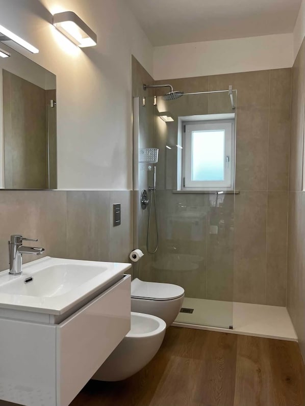 Un baño moderno con ducha de vidrio, inodoro y lavamanos.
