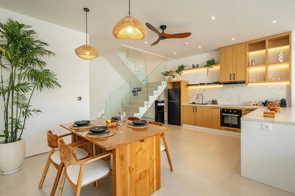 Une cuisine moderne avec des meubles en bois, un îlot central et un escalier en verre.