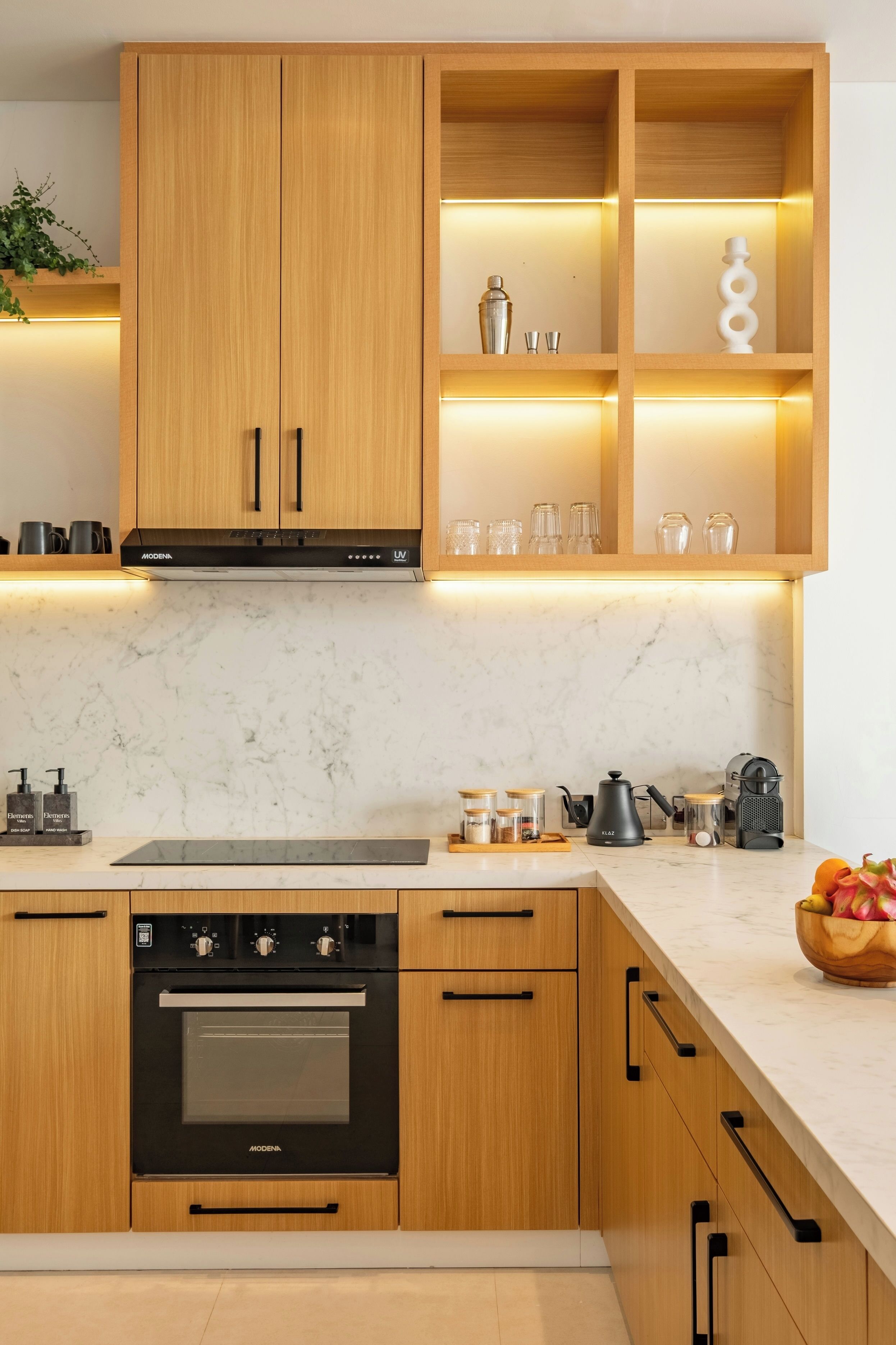Une cuisine moderne avec des meubles en bois, un four encastré et un plan de travail en marbre.