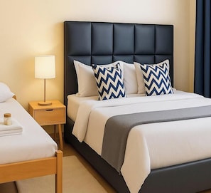 A hotel room with a bed, a nightstand, a lamp, and a bedside table. - Noaz Hotel (Kampala)