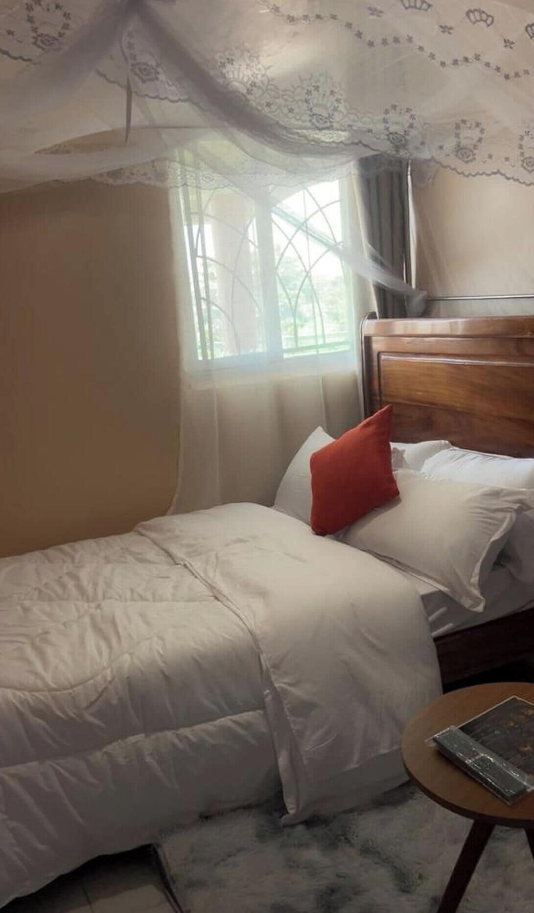 A bedroom with a bed, a small round table, and a window with a view.