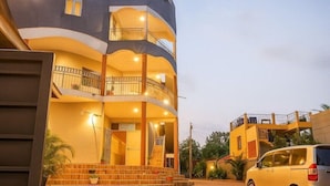 A multi-story building with balconies, a staircase, and a parked car. - Noaz Hotel  (Kampala)