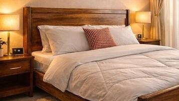 Un dormitorio con cama de madera, ropa de cama blanca, una alfombra mullida, una mesita de noche con lámpara y un cuadro abstracto colgado en la pared.