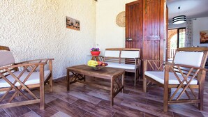 A rustic wooden dining area with a table set for four, chairs, and a bowl of fruit. - Villa Eugenie with pool (Sardegna)