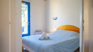 A bedroom with a bed, a blue door, and a white wall.