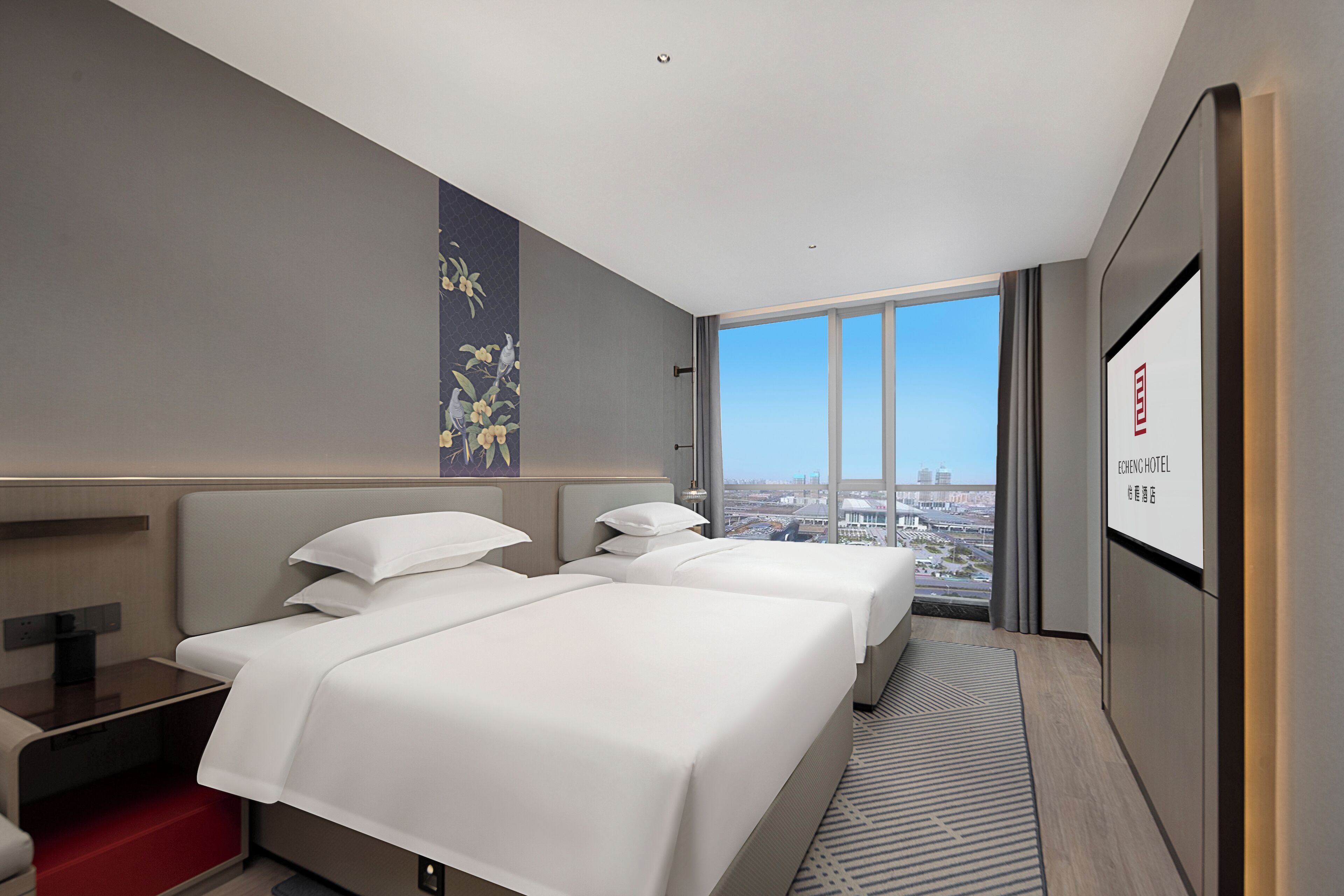 A hotel room with two beds, a large window with a city view, a wall-mounted TV, and a red step leading to a lower level.