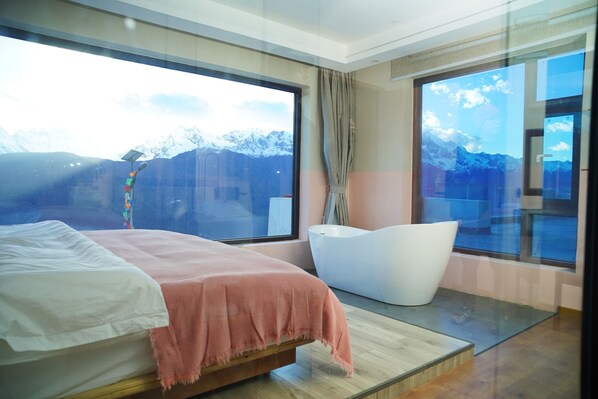 A modern bedroom with a large bed, a white bathtub, and a view of snow-capped mountains through large windows. - Wake UP IN SNOW MOUNTAIN (Deqin)