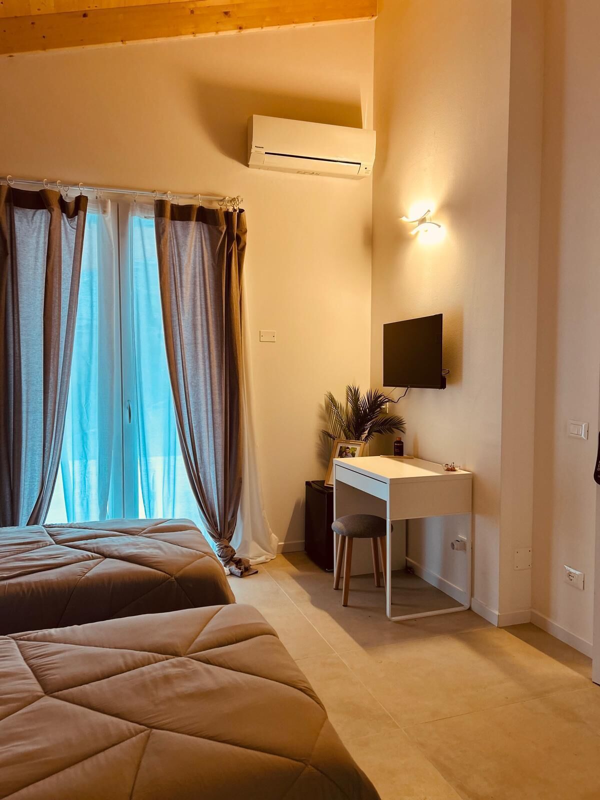 A bedroom with a bed, a desk, and a TV.