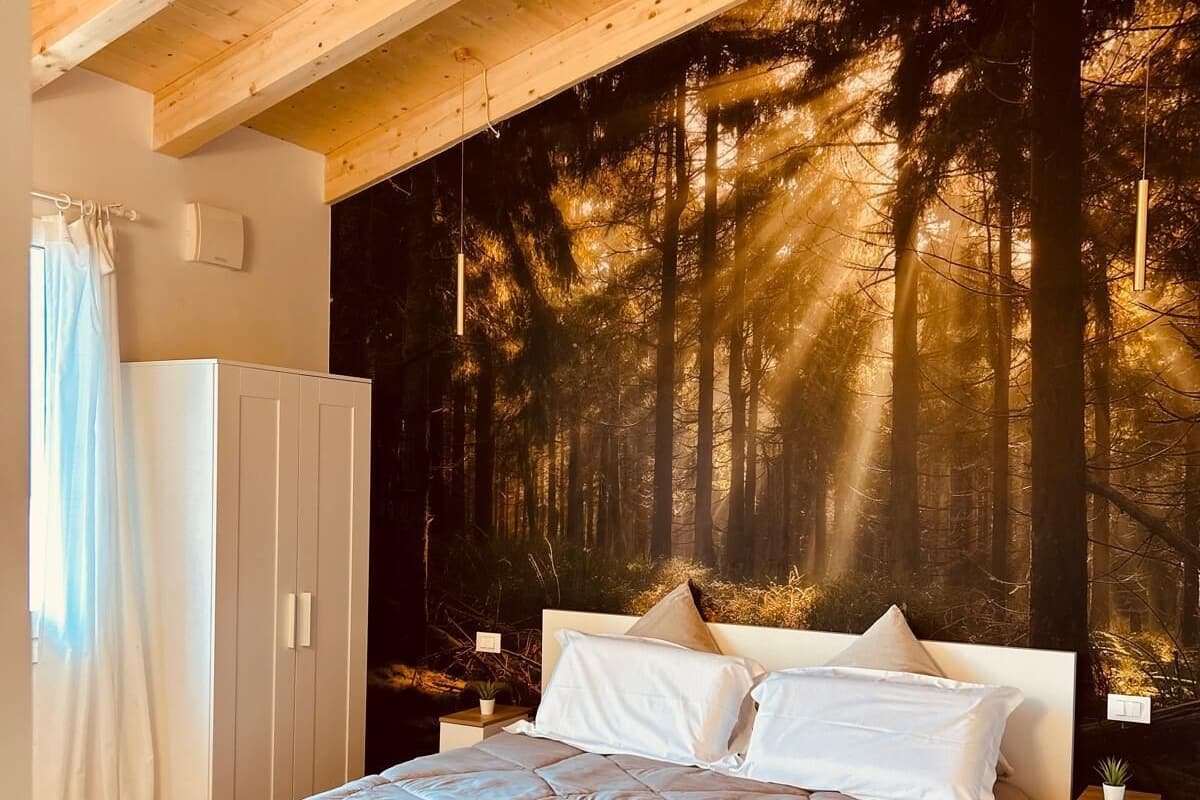 Un dormitorio con una cama grande, un mural temático de bosque y techo de madera.