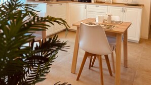 Een moderne keuken met witte kasten, een houten eettafel en een plafond met zichtbare balken.