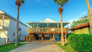 A two-story building with a balcony, palm trees, and a clear sky. - Coastal Retreat w/ Pool,  BBQ & Sunset Views | Beers and Sunshine by AvantStay (Port Aransas)