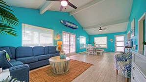 A living room with a blue sofa, a round coffee table, and a ceiling fan. - Coastal Retreat w/ Pool,  BBQ & Sunset Views | Beers and Sunshine by AvantStay (Port Aransas)
