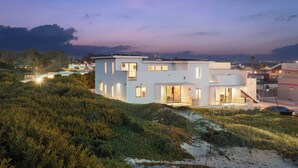 A modern two-story house with a flat roof, large windows, and a balcony. - Oceanfront 2BR + Rooftop Deck, & Beach Access | Strand Way B (Oceano)