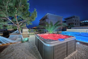 Relax in a serene outdoor space with a hot tub, hammock, and pool.