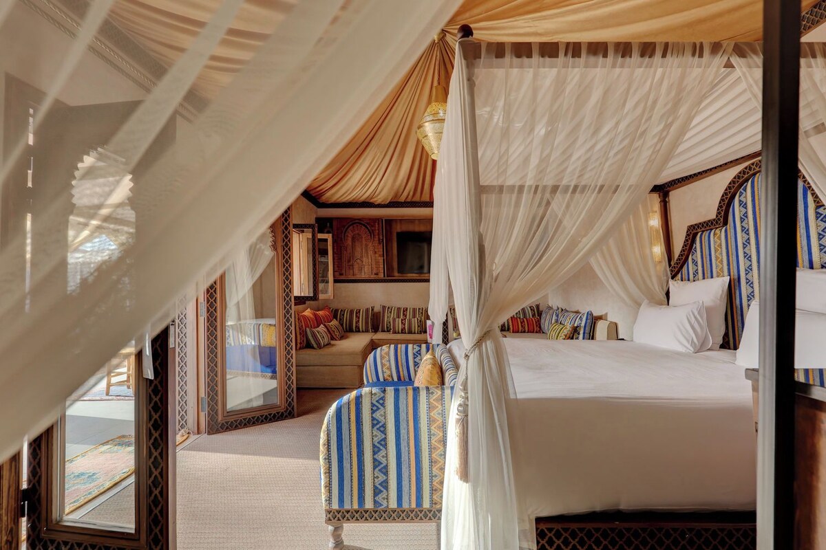 A room with a bed, a sofa, and a window.