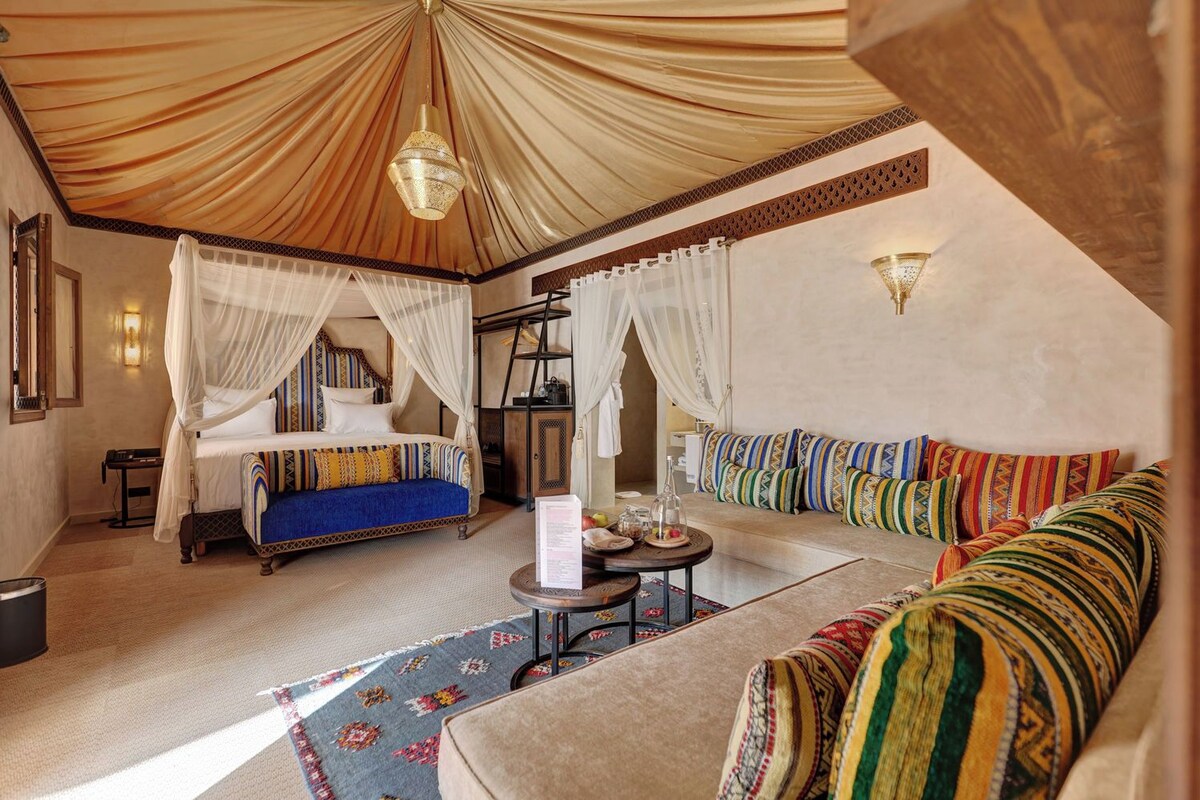 Una habitación con una cama, un sofá, una mesita y un techo decorado.