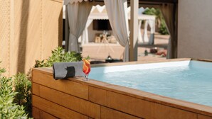 A swimming pool with a towel and a drink, surrounded by wooden deck and greenery. - Palmeraie Oasis Camp - A Member Of Barcelo Hotel Group (Marrakech)