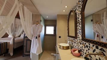 A hotel room with a bed, a bathroom with a large mirror, and a sink.