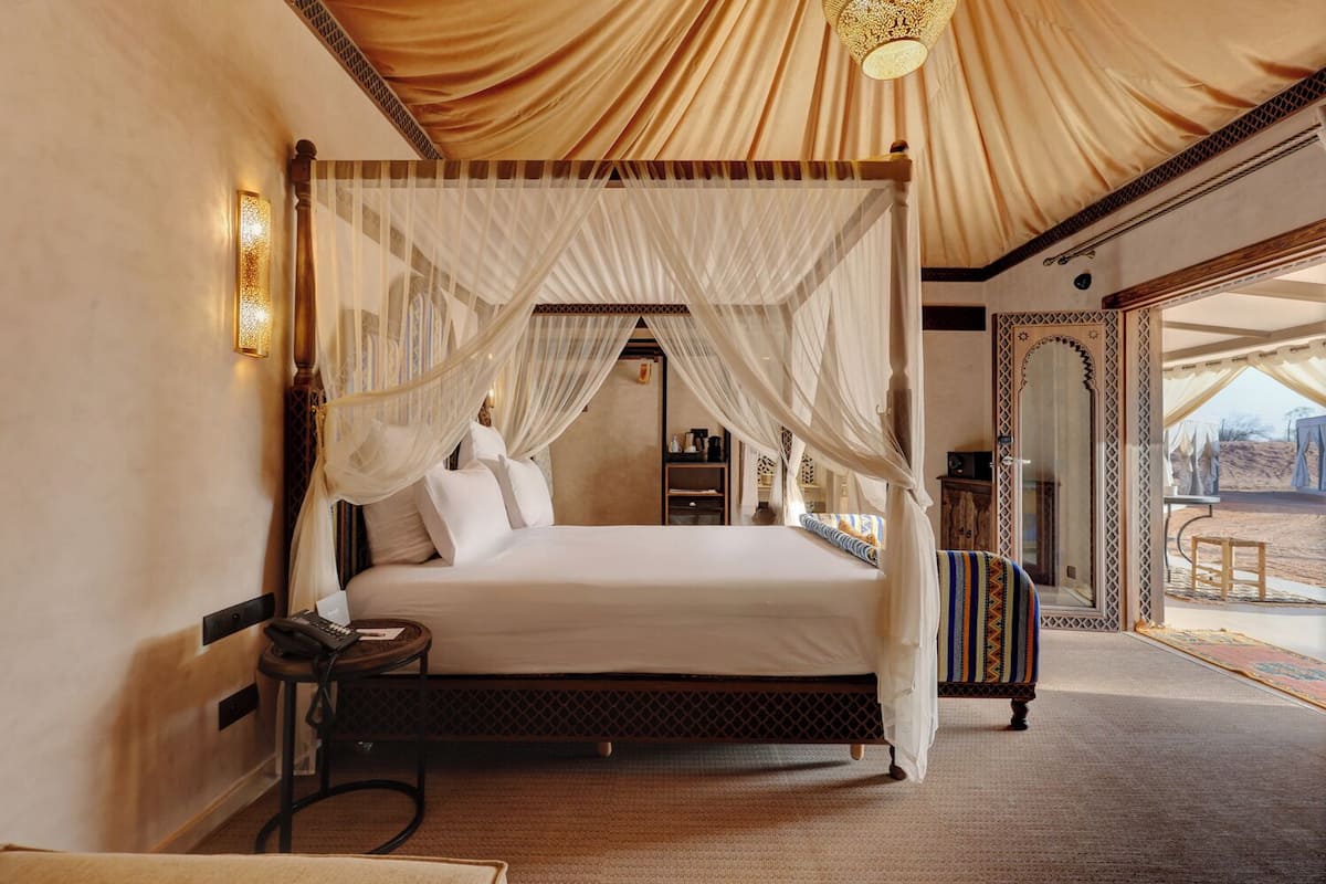 Ein Zimmer mit Bett, Nachttisch, Lampe und Blick ins Freie.