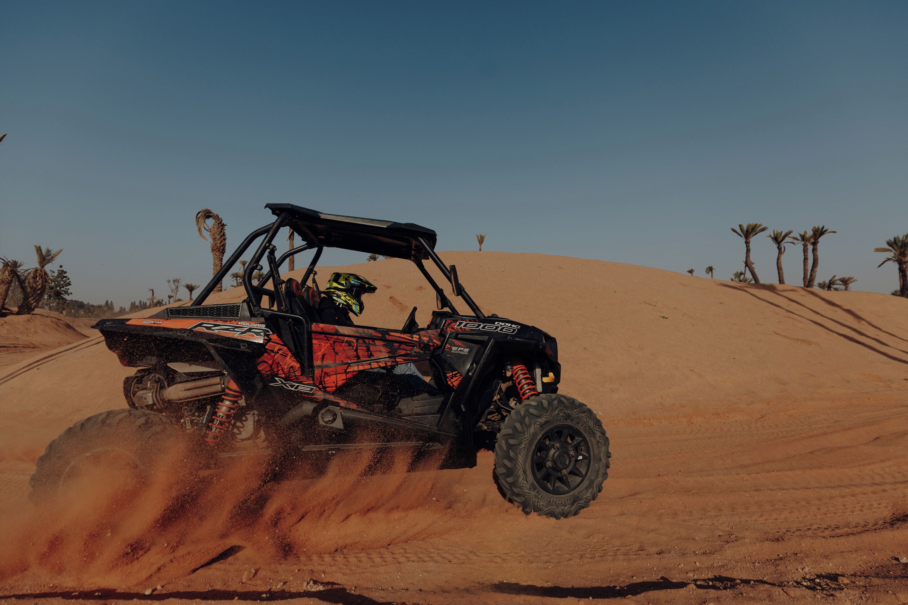 A desert off-road vehicle driving through sand dunes.