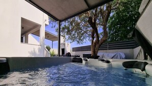 Bereich mit Whirlpool, Baum, überdachter Sitzgruppe und modernem architektonischen Design.