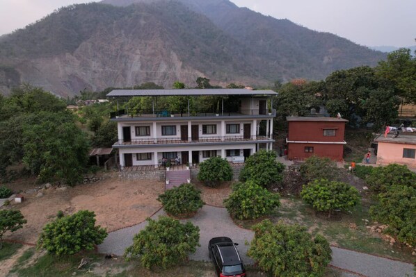 A two-story building with a balcony, surrounded by trees and a mountain in the background. - Kattapathar Nature Resort (Vikasnagar)
