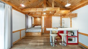Habitación pequeña con cama, kitchenette y baño.