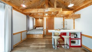Habitación pequeña con cama, kitchenette y baño.