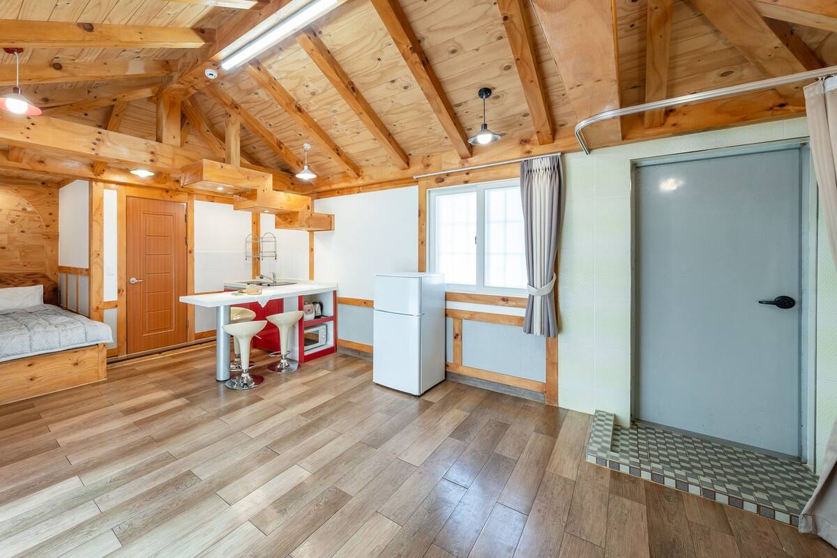Interior acogedor de una cabaña con techo de madera, una cama, kitchenette y baño.