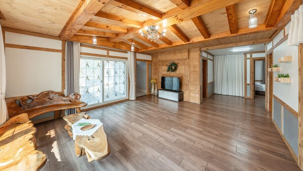 Amplia sala de estar con pisos de madera, un banco de madera, un televisor y una chimenea.