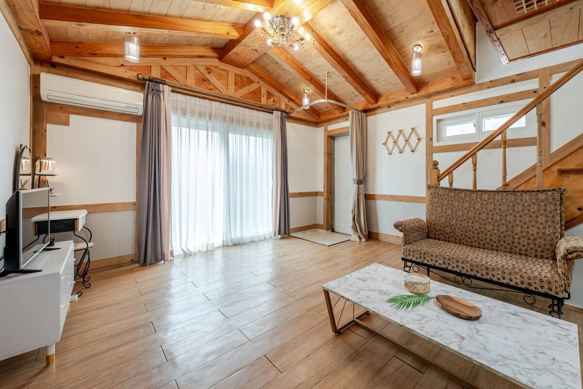 Amplia sala de estar con pisos de madera, un sofá, una mesa de centro y una escalera.