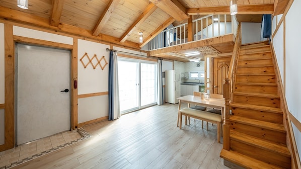 A spacious room with a wooden staircase, a dining area, and a kitchen visible through an open door. - Gapyeong Iris Pension (Gapyeong)