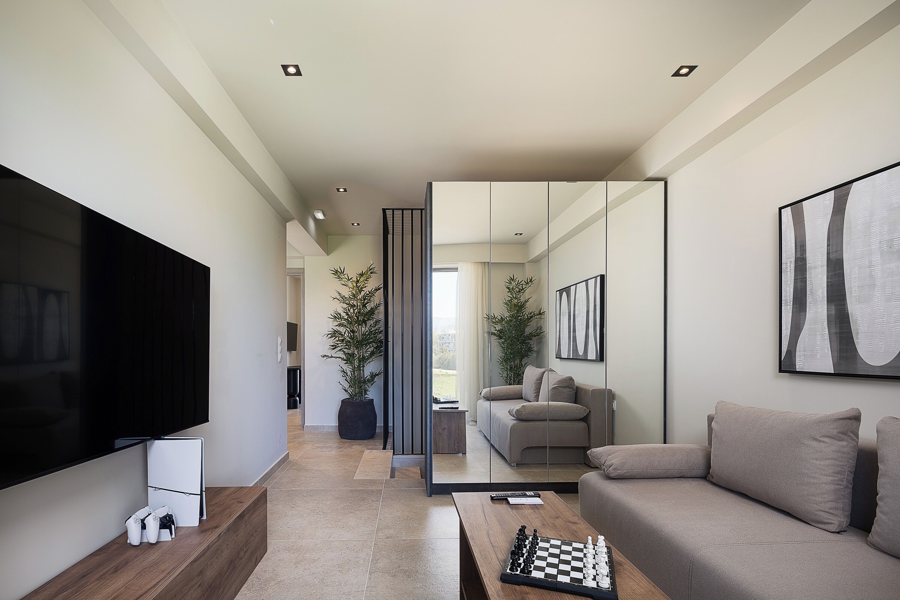 A modern living room with a flat-screen TV, a wooden coffee table, and a beige sofa.