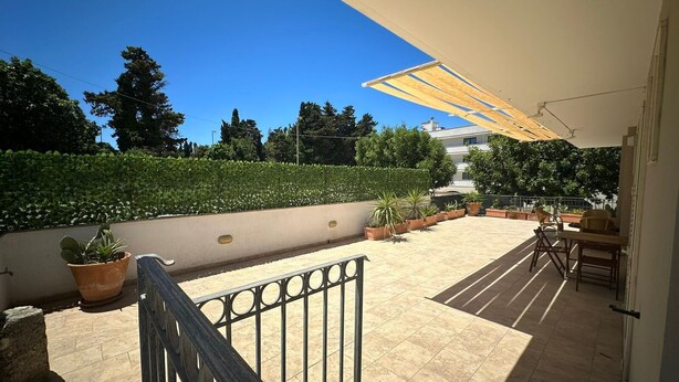 A sunlit patio with tiled flooring, potted plants, outdoor furniture, and a metal railing. - Andromeda Rooms Otranto (Otranto)