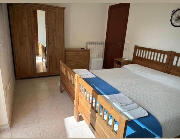 A bedroom with a wooden bed, a wardrobe, a dresser, and a mirror.