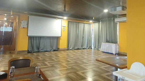 A conference room with a wooden floor, a projector screen, and a whiteboard.