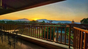 A balcony with a view of a sunset over mountains, a pool, and a sign reading "MAP RESORT". - Map Resort (Alibag)