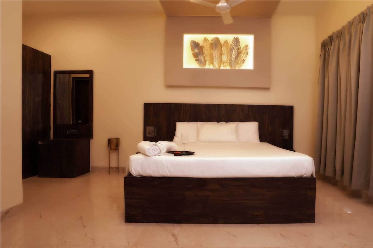 Quarto de hotel com uma cama grande, cabeceira de madeira escura, uma obra de arte na parede, televisão de tela plana e uma janela ampla com cortinas.