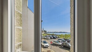 A parking lot with cars and a view of a body of water and a distant shoreline.