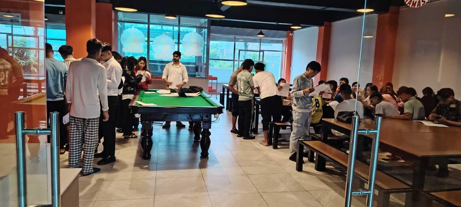 A billiards hall with a pool table, multiple seating areas, and large windows.