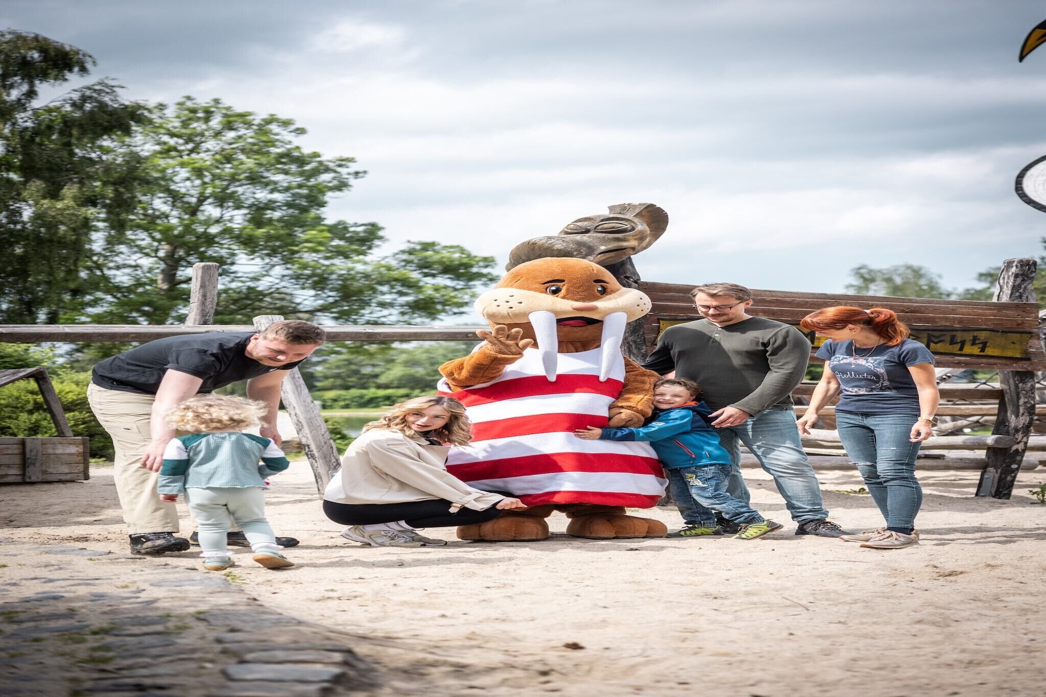 Ein Maskottchen interagiert mit einer Gruppe von Menschen im Freien.