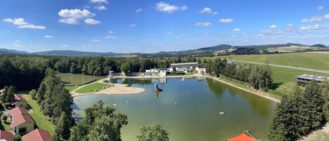Una propietat a la vora d'un llac, amb un estany gran, una pista de tennis i un edifici amb teulada vermella.