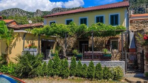A yellow building with a red roof, surrounded by greenery and a mountainous backdrop. - Adorable home with bubble bath (Bribir)