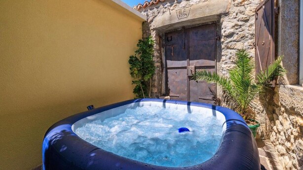 An inflatable hot tub in a courtyard with a stone wall and a wooden door. - Adorable home with bubble bath (Bribir)