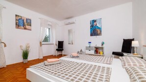 A room with two beds, a desk, a chair, a potted plant, and artwork on the walls. - Adorable home with bubble bath (Bribir)