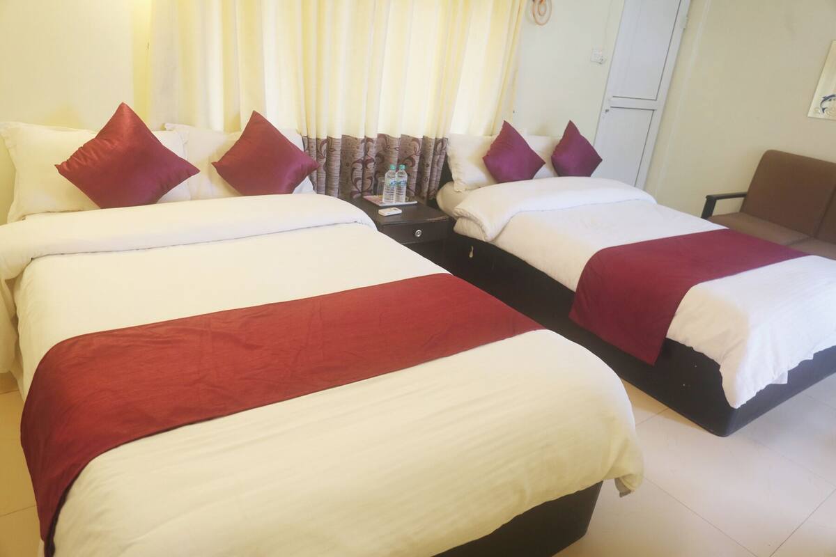 A hotel room with two beds, each with white and red bedding, and a small table with a bottle and a menu.