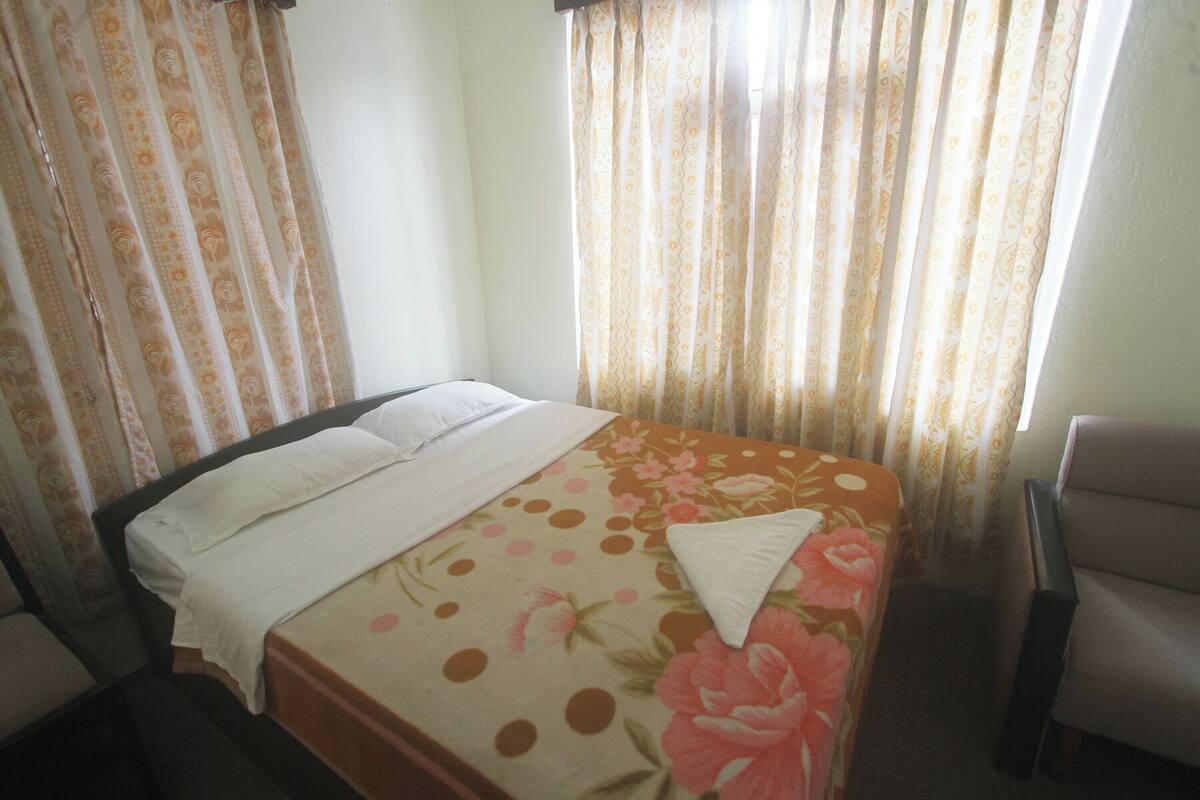 A hotel room with a bed, a chair, and curtains.