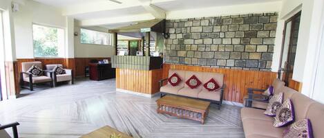 A spacious lobby with a stone wall, wooden paneling, and seating areas.